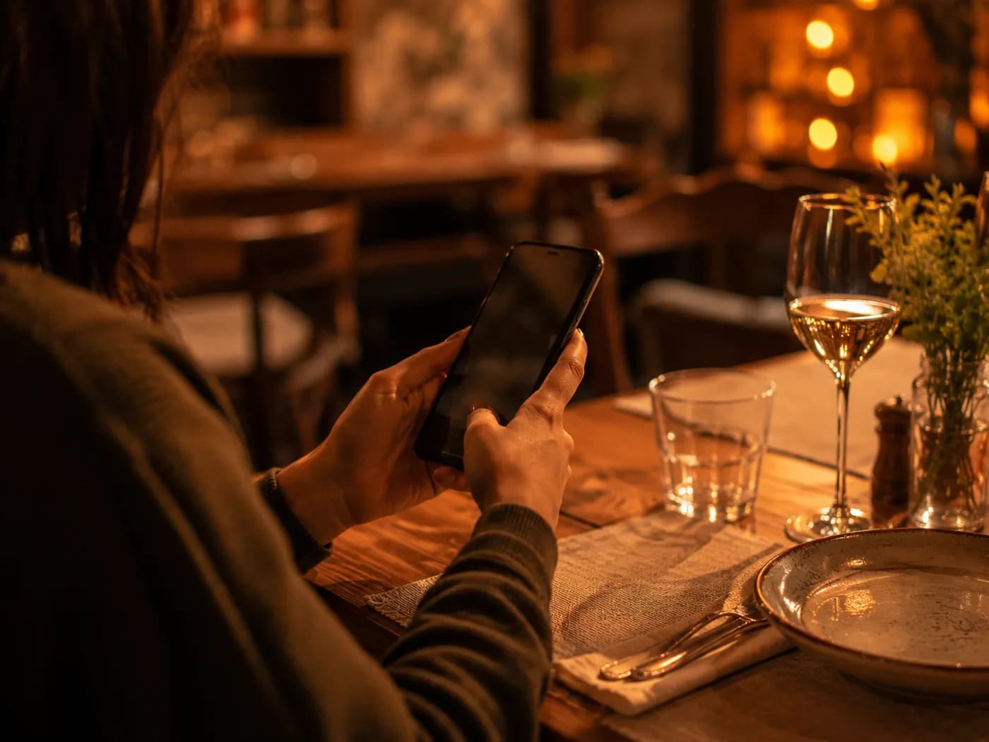 A guest holding a phone at a restaurant table